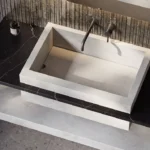 Caesarstone Quartz 4044_Airy Concrete surface in Modern rectangular stone sink with wall-mounted faucet, soap dispenser, and minimalist countertop design.