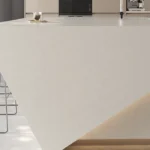 Caesarstone Quartz 4600 Organic White surface in Modern kitchen island with unique angular design, bar stools, and natural light from large windows.