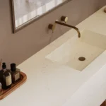 Caesarstone ICON 5141 Frosty Carrina in Minimalist bathroom sink with brass faucet, pendant light, toiletries on wooden tray, and wicker basket.