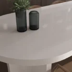 Caesarstone Quartz 6141 Ocean Foam surface in White oval table with two dark vases and brown chairs around it.