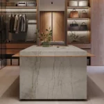 Spacious walk-in closet with hanging clothes, shelves, handbags, drawers, and marble island.