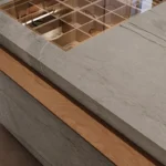 Marble countertop with wooden edge and built-in grid display case, vase with green leaves.