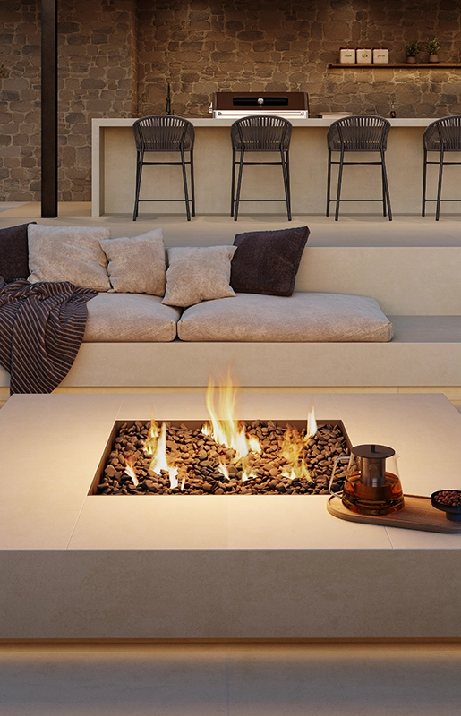 Modern outdoor lounge with cushioned seating, central fire pit, bar area, and scenic waterfront view.